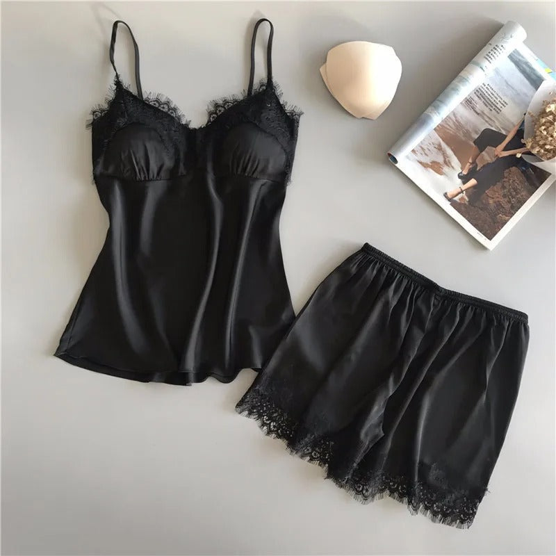 Kvinne i elegant sateng nattøysett med shorts og V-hals, slapper av hjemme. Perfekt for søvn og velvære.