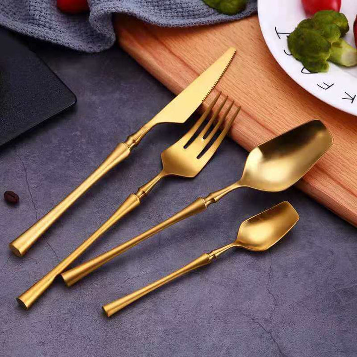 Elegant bestikksett for fire, i skinnende gullfarger av rustfritt stål til middag.
