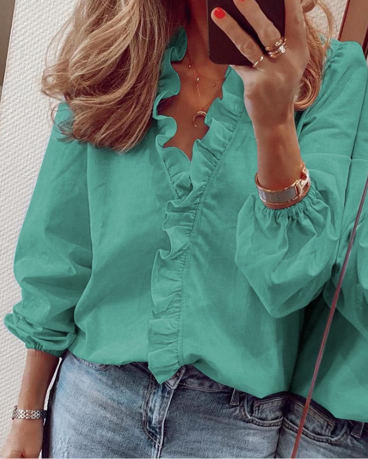 Motebevisst kvinnebluse med V-hals og volangdetaljer, en trendy topp som passer til ulike antrekk.